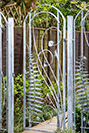 A garden gate made with flowing curves, stylised plants and fern sculptures